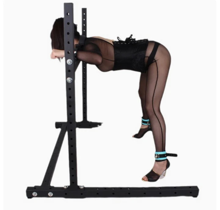 Multi-Position Bondage Stand System with model, heavy-duty adjustable BDSM furniture featuring reinforced frame, padded supports, and multi-point restraint system shown in use for secure positioning and stability.