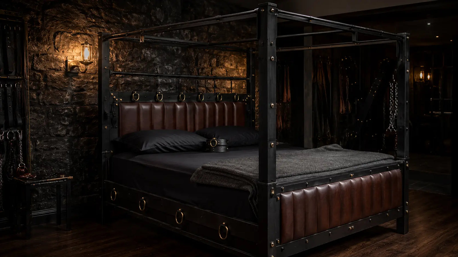 remium king-size BDSM bed with leather-padded metal frame, brass D-rings, and overhead cage frame in a moody dungeon-style bedroom, BDSM Authority