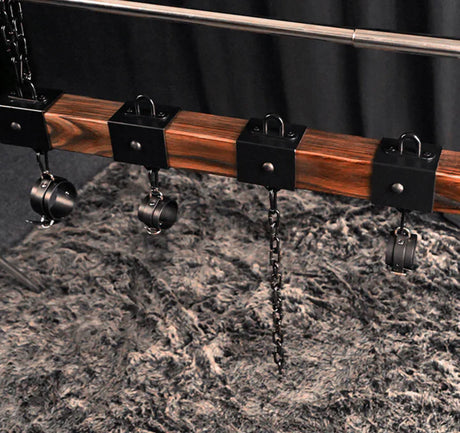 Elm wood spreader bar shown with three cuffs along the carbonized elm bar - BDSM Authority