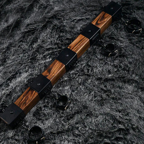 Elm wood spreader bar shown with four cuffs along the carbonized elm bar for multi-point restraint - BDSM Authority