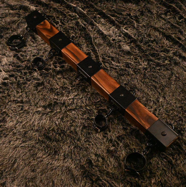 Elm wood spreader bar point-of-view angle showing cuffs and steel hardware for positioning - BDSM Authority