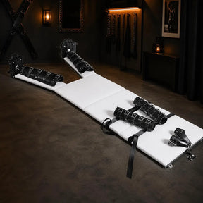 Heavy-duty bondage bed with padded restraints displayed in a luxury dungeon room setting