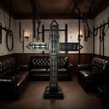 Luxury padded black BDSM cross displayed in a premium dungeon lounge with dark leather seating, wall-mounted restraints, and moody ambient lighting. High-end freestanding St. Andrew’s cross for luxury BDSM room design and professional dungeon setups.